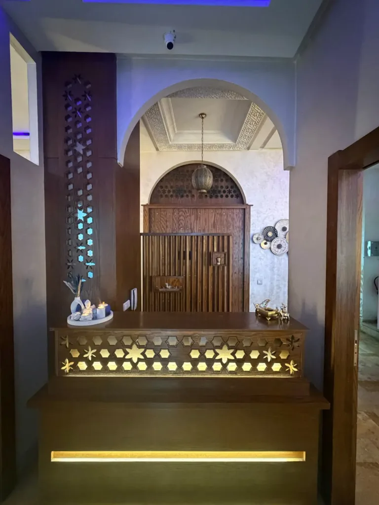 Comptoir d'accueil en bois sculpté sous une arche marocaine chez Yanis Prestige Spa à Casablanca