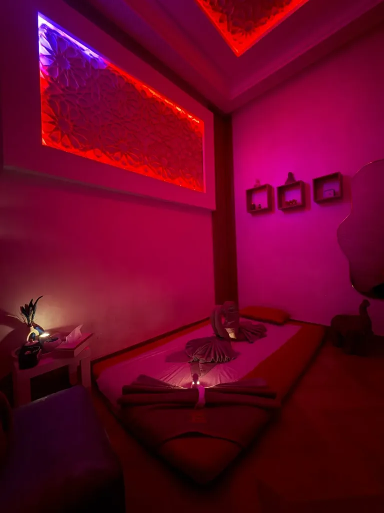 Cabine de massage au sol avec serviettes pliées et panneau sculpté rétroéclairé chez Yanis Prestige Spa