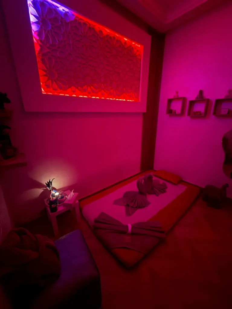 Matelas de massage au sol, serviettes pliées et étagères décoratives chez Yanis Prestige Spa