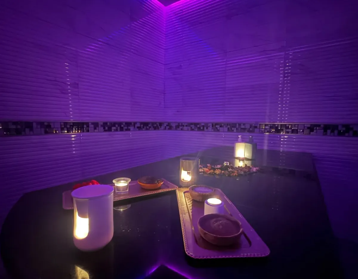 Table de gommage en marbre noir éclairée à la bougie dans le hammam de Yanis Prestige Spa