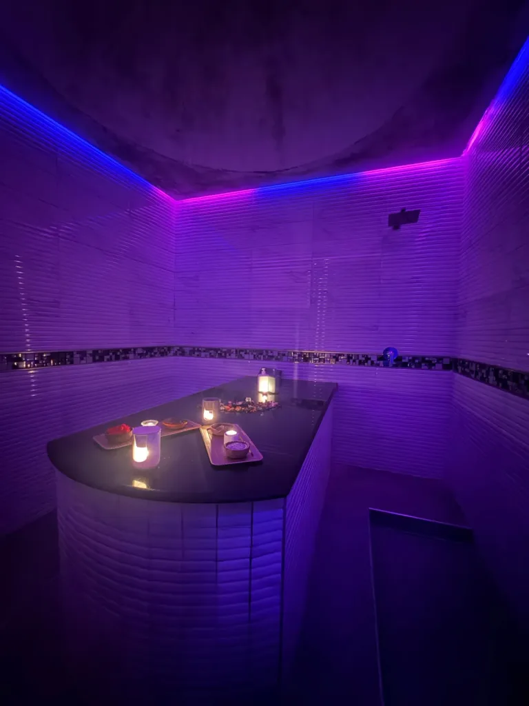 Hammam traditionnel de Yanis Prestige Spa à Casablanca, murs en pierre claire et lumière violette