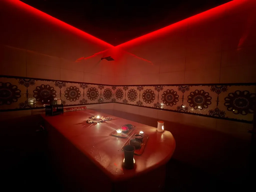 Salle de hammam ornée d'une frise en zellige et éclairée d'une lumière rouge chez Yanis Prestige Spa